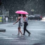 Gente cammina in estate sotto la pioggia