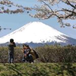 L'iconico Monte Fuji in Giappone sullo sfondo, in primo piano una famiglia che lo fotografa