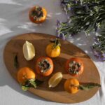 dei cachi e degli agrumi sopra ad un tagliere di legno