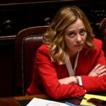 giorgia meloni in rosso, guarda perplessa