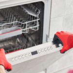 mani sul coperchio di una lavastoviglie