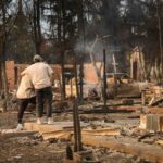 coppia abbracciata davanti alle macerie della loro casa distrutta negli incendi di Los Angeles