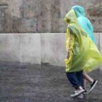 Due persone camminano con l'impermeabile