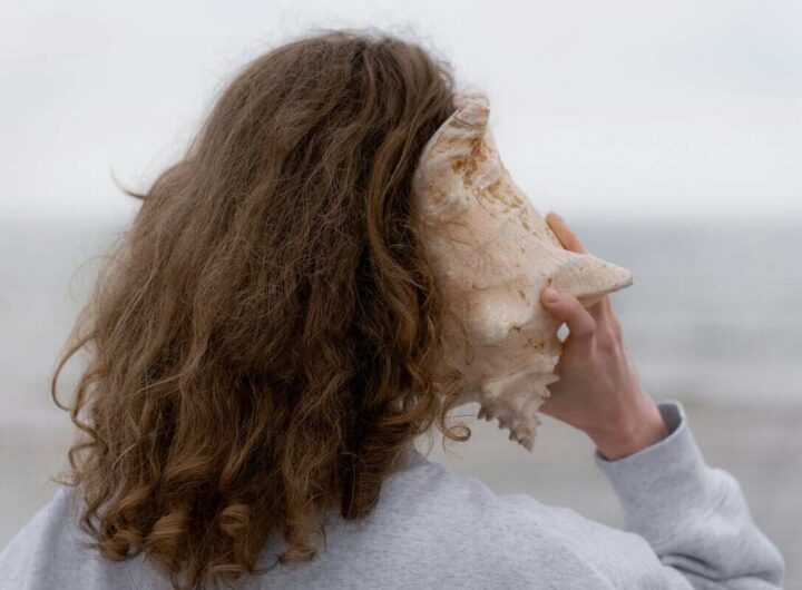 una ragazza al mare ascolta dentro una conchiglia
