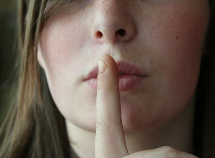 Una donna con l'indice alla bocca in segno di silenzio