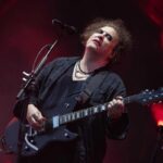 Robert Smith dei Cure, suona la chitarra davanti a un microfono durante un'esibizione dal vivo