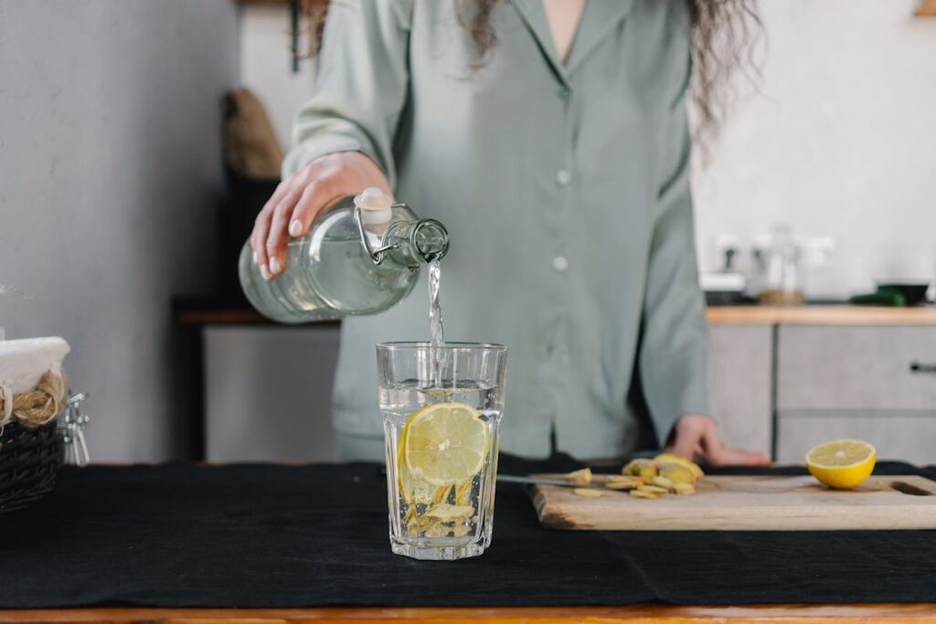una donna versa acqua in un bicchiere con il limone