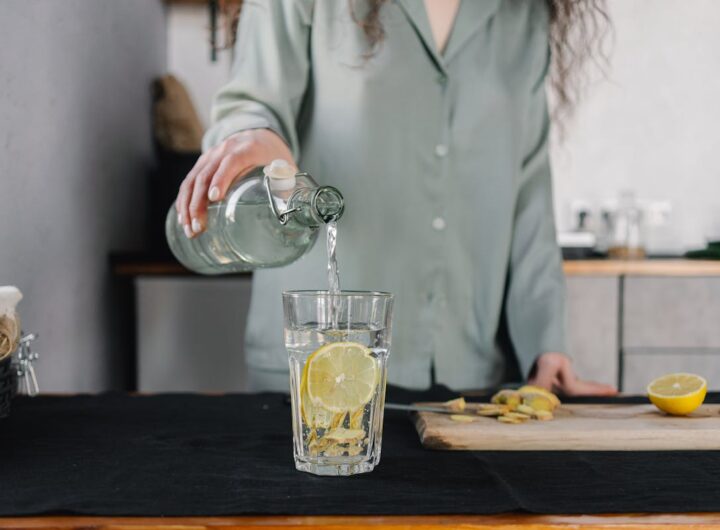 una donna versa acqua in un bicchiere con il limone