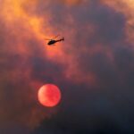 L'elicottero dei pompieri tra il fumo e le fiamme per spegnere l'incendio nei boschi in Val Venosta