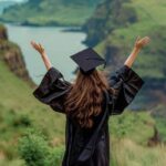 Ragazza laureata con le braccia aperte di fronte a un paesaggio