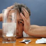 uomo davanti ad un bicchiere con una aspirina