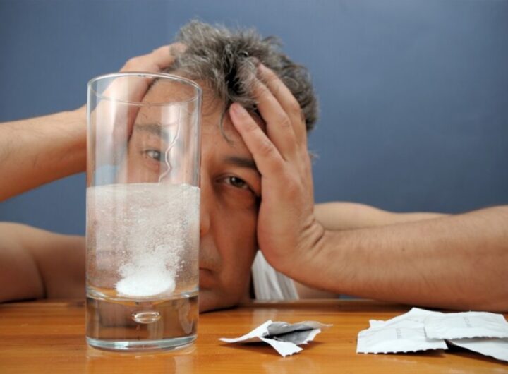 uomo davanti ad un bicchiere con una aspirina