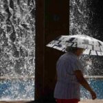 Una donna si ripara dal sole con un ombrello