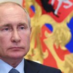 Trump ha subito, ora Zelensky e l’Europa devono ingoiare: le ragioni di Putin, le paure dei Baltici , Nela foto Vladimir Putin sullo sfondo della bandiera russa