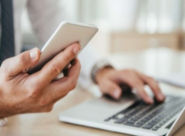 Uomo al computer con telefonino in mano