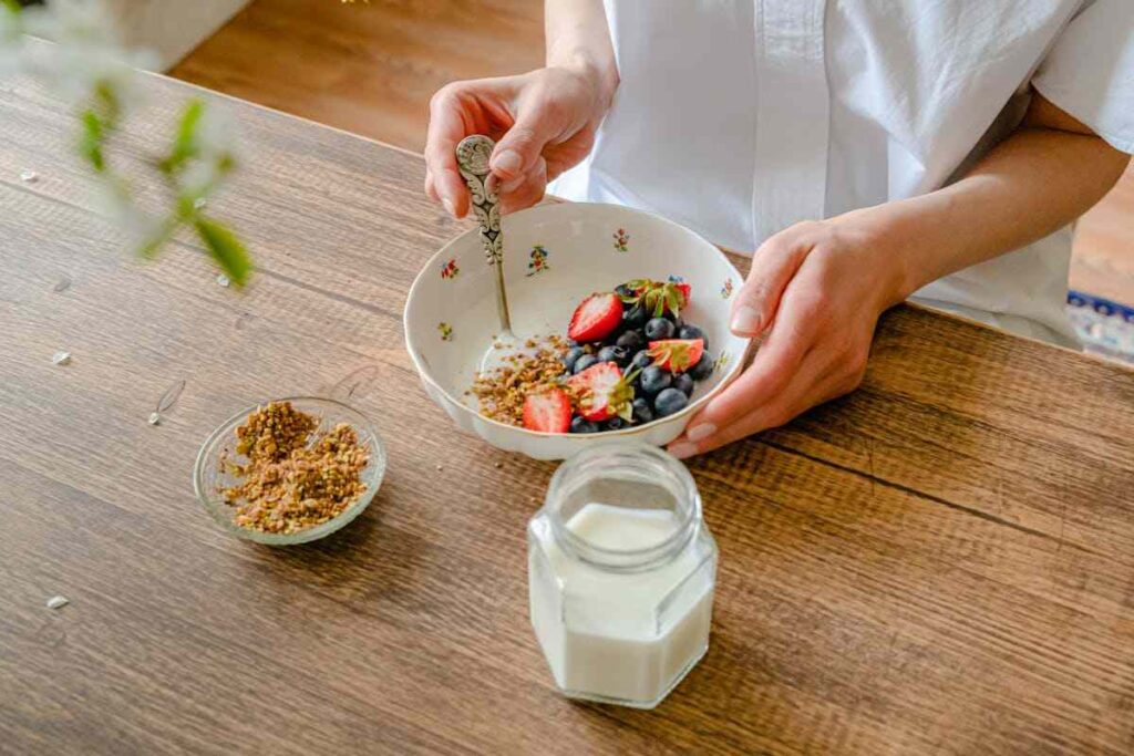 una donna fa colazione con yogurt e frutta