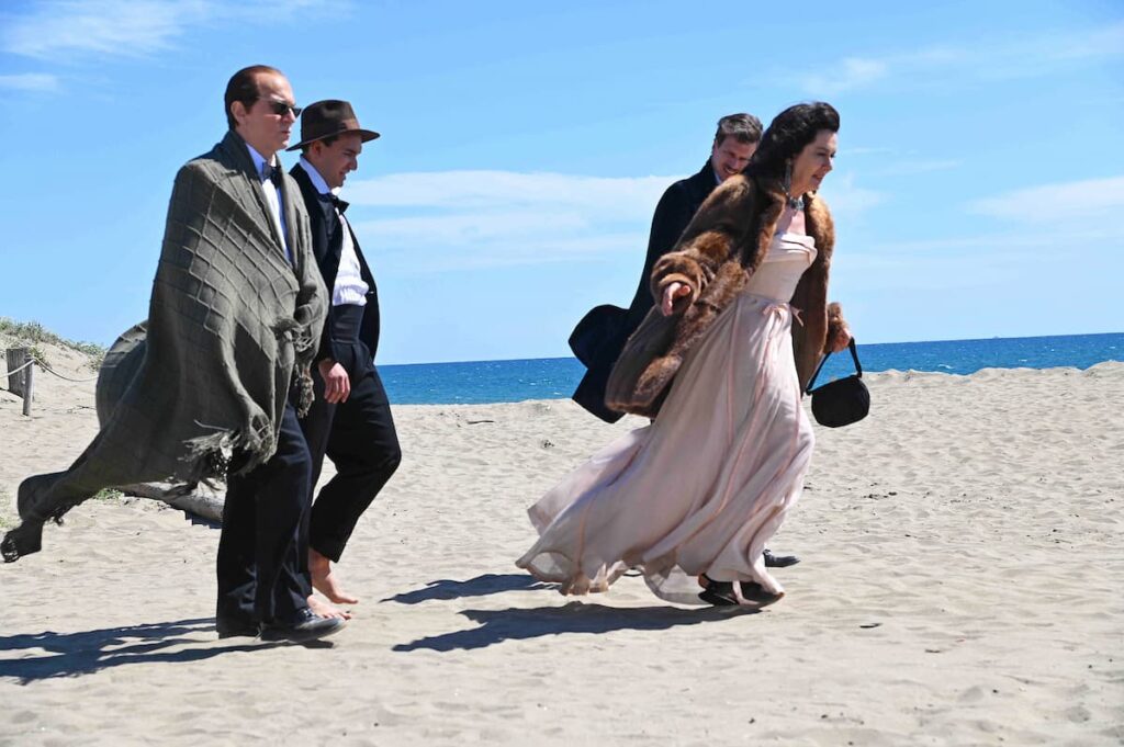 3 uomini e una donna in abiti da sera camminano sulla spiaggia di giorno