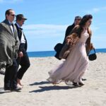 3 uomini e una donna in abiti da sera camminano sulla spiaggia di giorno