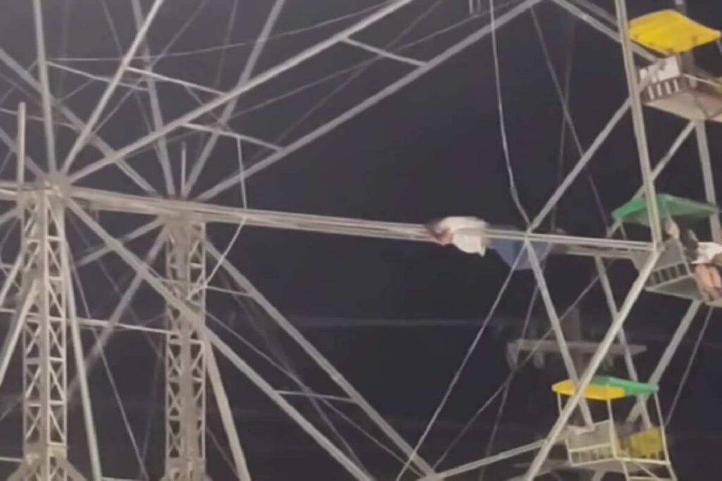 Uomo appeso alla struttura metallica di una ruota panoramica