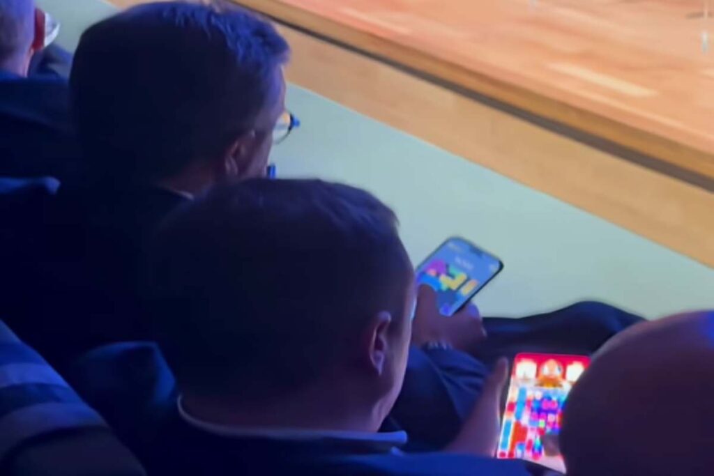 Sindacalisti giocano al cellulare durante l'intervento del ministro Urso