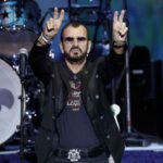 Ringo Starr su un palco fa il segno della pace