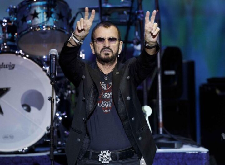 Ringo Starr su un palco fa il segno della pace
