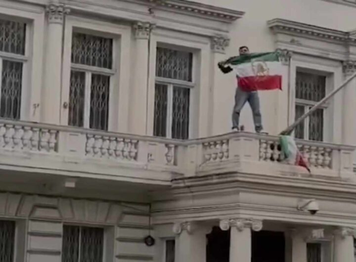 manifestante sostiuisce bandiera iraniana all'ambasciata a Londra