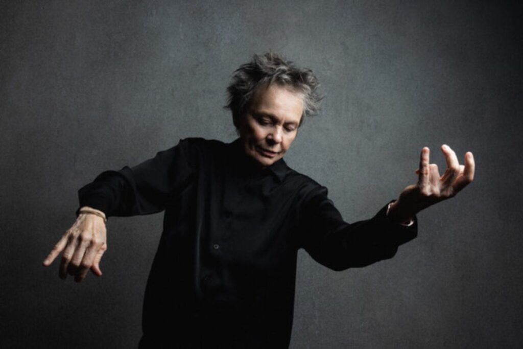Laurie Anderson in posa come se suonasse un violino immaginario.