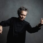 Laurie Anderson in posa come se suonasse un violino immaginario.