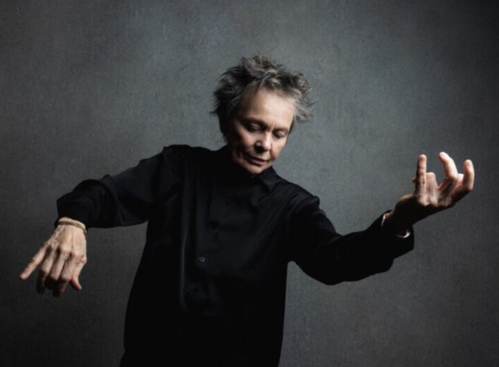 Laurie Anderson in posa come se suonasse un violino immaginario.
