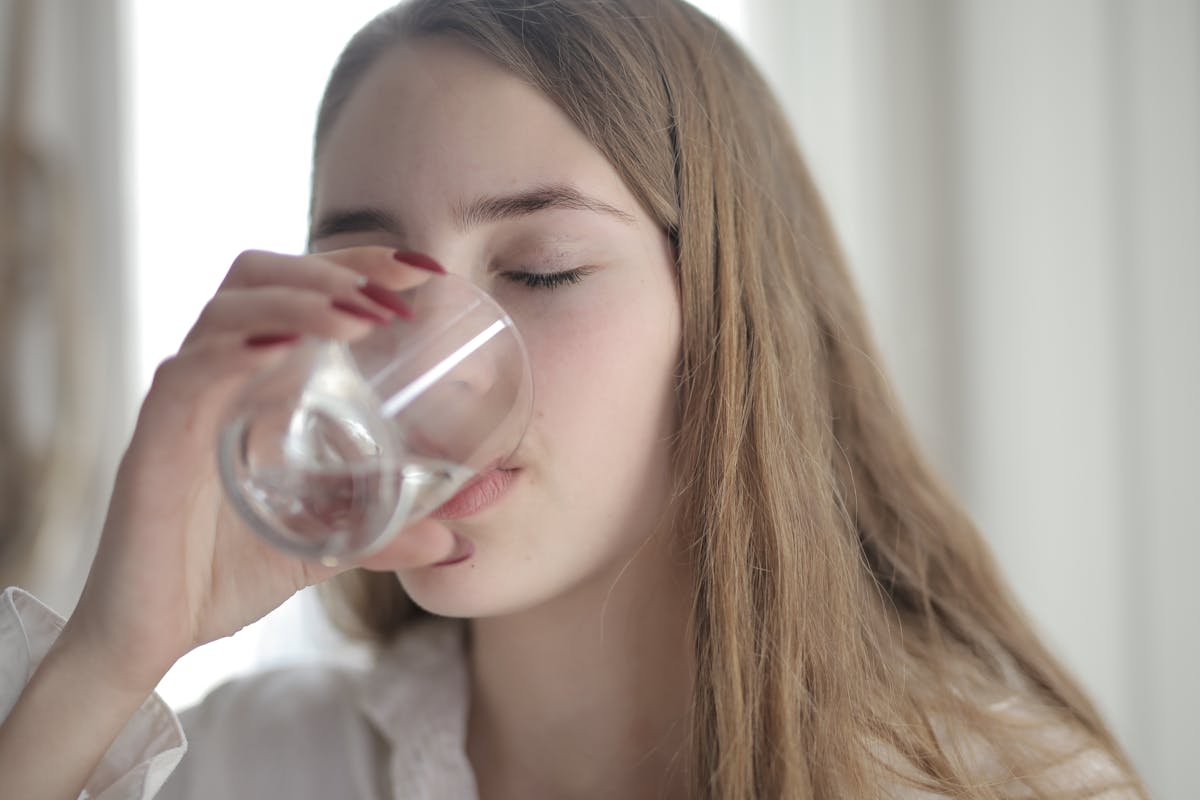 una ragazza beve acqua da un bicchiere