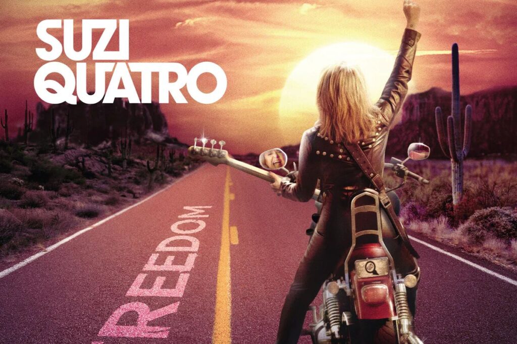 La copertina di Freedom di Suzi Quatro, con la bassista di spalle su una moto, con un basso in braccio, vestita di pelle, su una strada diretta verso il tramonto con la scritta "Freedom" e un braccio alzato verso il cielo
