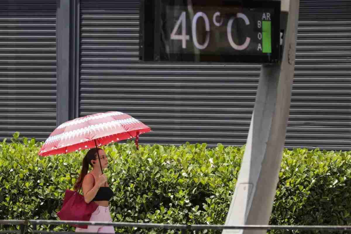 In strada fanno 40 gradi, donna passeggia con ombrello