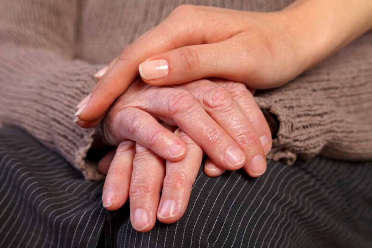 Mano di donna giovane sopra quella di un anziano
