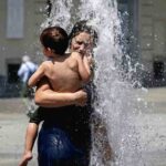 Donna si rinfresca sotto l'acqua