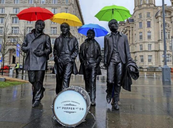 La statua dei Beatles a Liverpool. I Fab Four sono immortalati mentre camminano uno a fianco all'altro. La foto, scattata per i 50 anni di Sgt. Peppers, mostra le statue con ombrelli colorati e una cassa di batteria con una scritta celebrativa sulla pelle