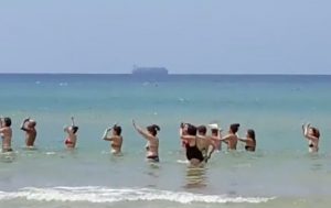 YOUTUBE Pozzallo, balli di gruppo in mare. Sullo sfondo la nave Maersk carica di migranti