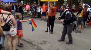 bambina sventola bandiera arcobaleno davanti a predicatore anti-gay
