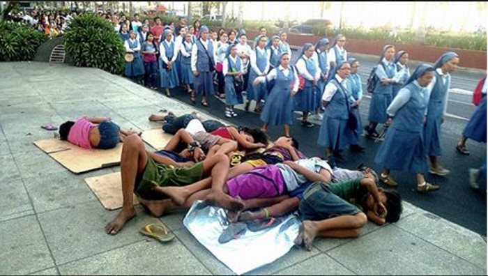Suore indifferenti passano accanto ai bambini che dormono in strada a Manila 